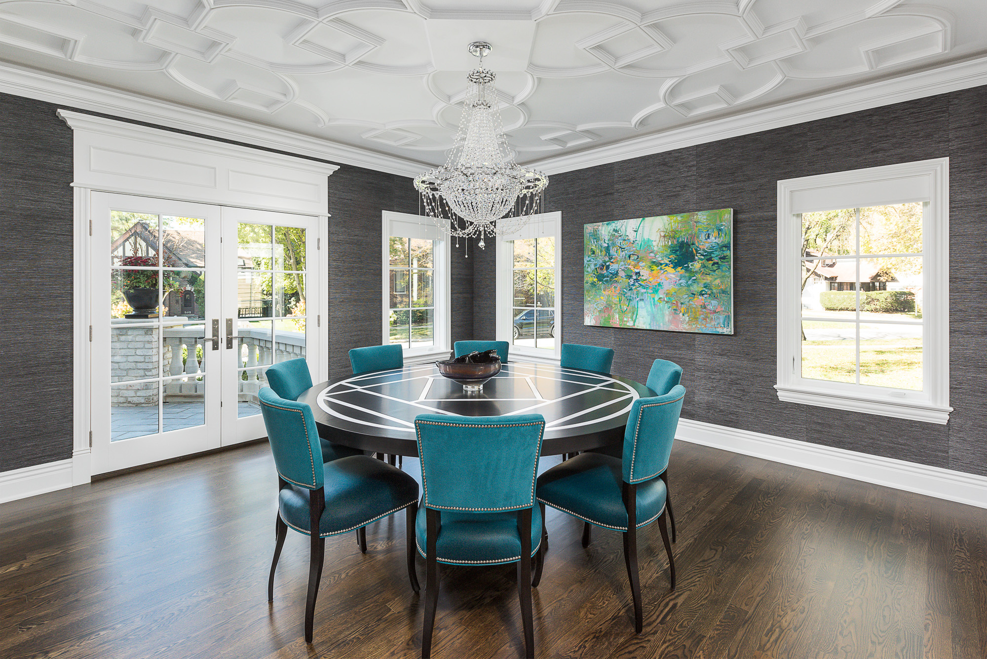 Dining room with three windows and french doors. The photo shows the custom moulding on the ceiling, crown moulding at the ceiling, and architrave above the french doors.