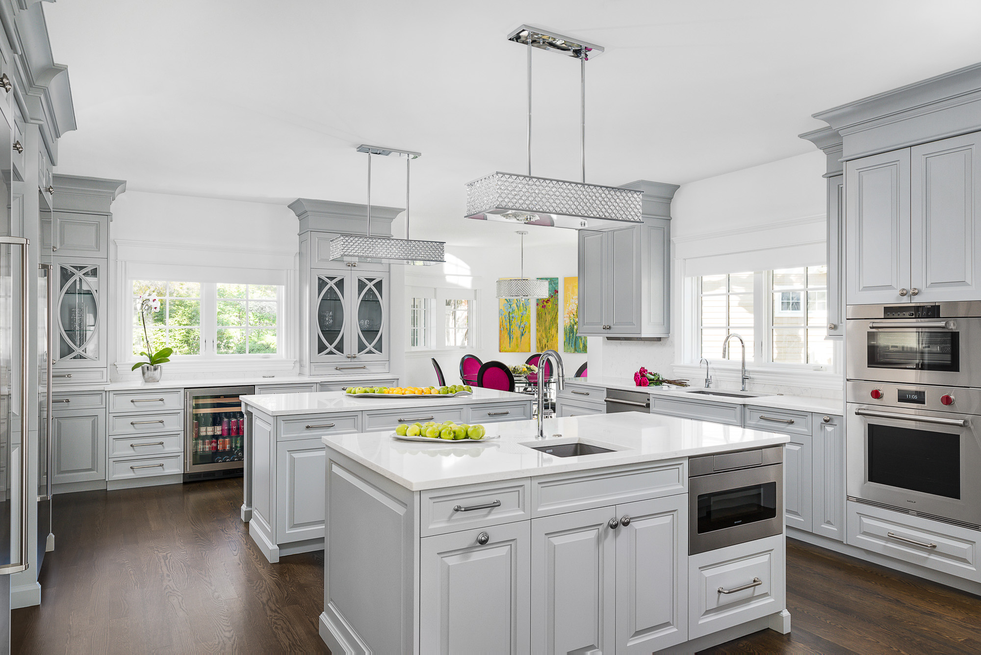 Luxury kitchen with dual islands, vegetable prep sink, white European cabinetry, custom mullion doors, M series wall oven, steamer, and microwave.